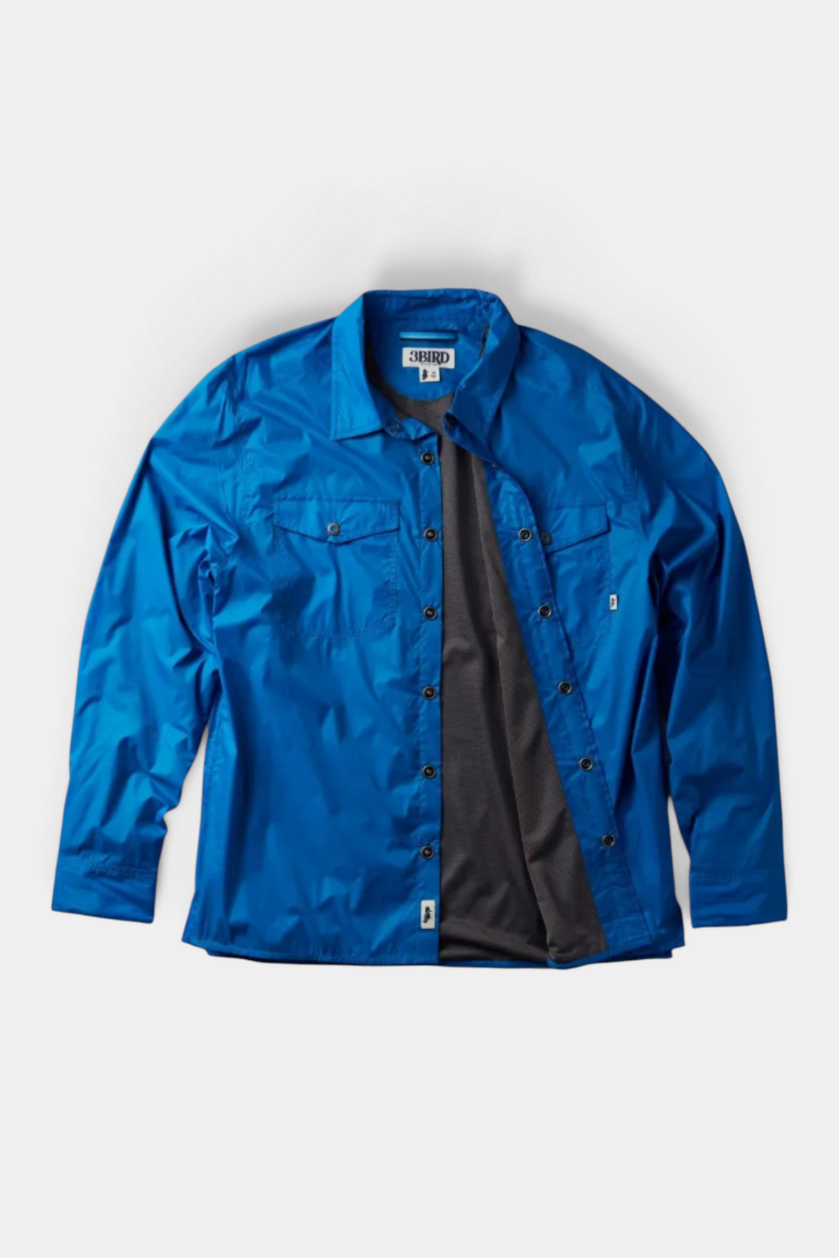 The Copper Shed Frigate Windshirt in bright blue with a dark grey lining, featuring button-down front and pockets.
