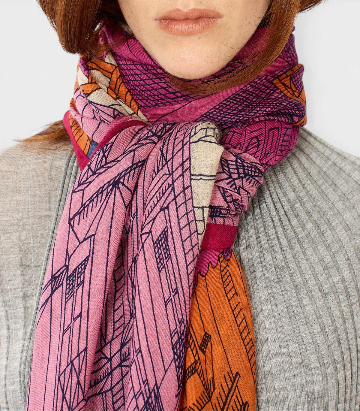 The Copper Shed fuchsia wool scarf with Paris-inspired graphic line drawings worn around a model's neck.
