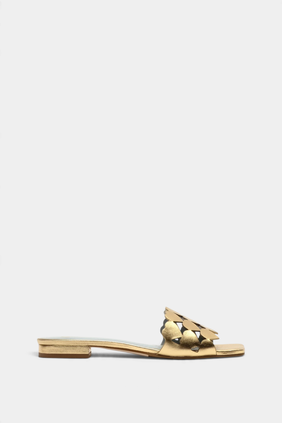 The Copper Shed gold leather flat slide sandals featuring three rows of decorative heart cutouts on the strap.