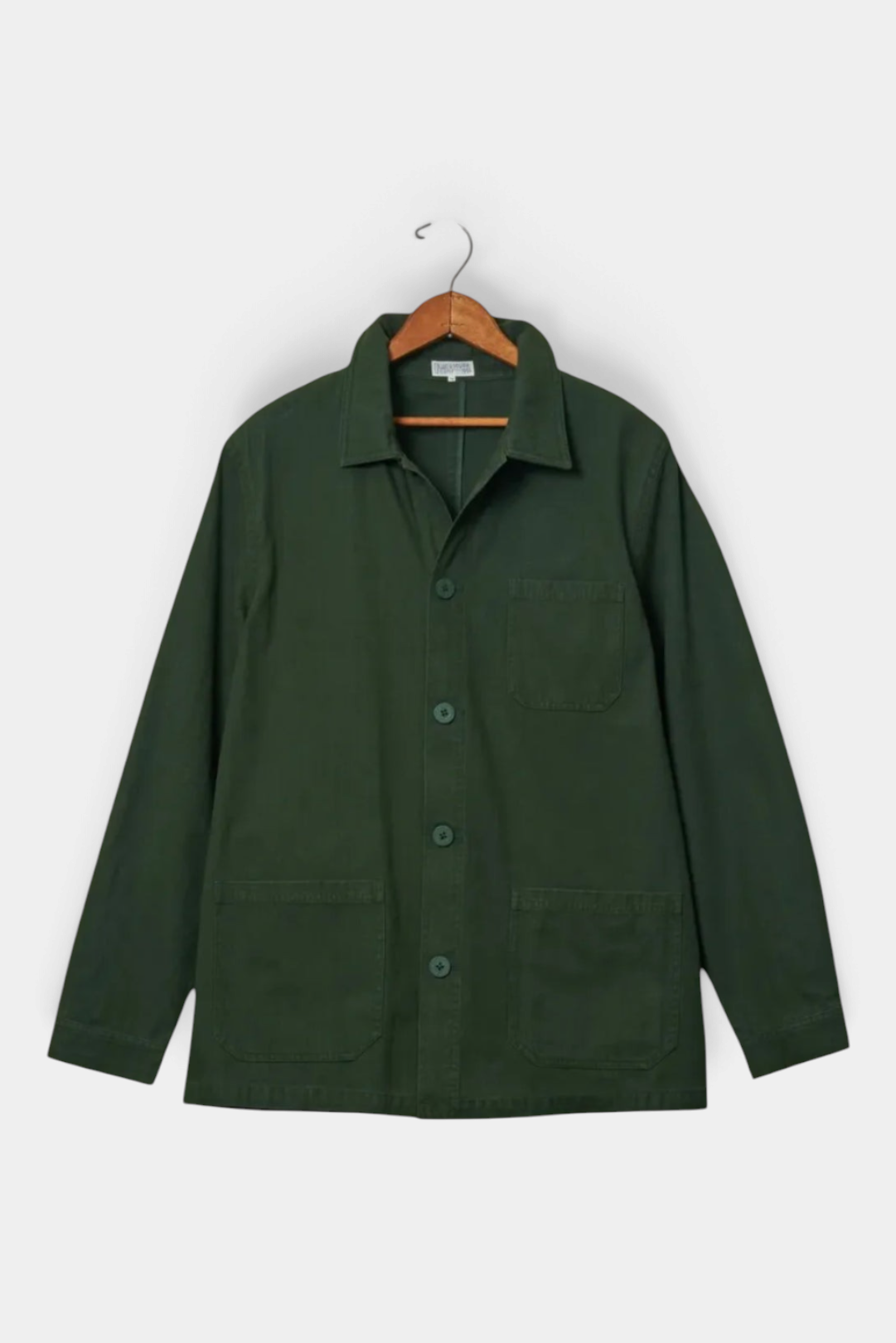 The Copper Shed dark green cotton French workman’s jacket with patch pockets and button-down front on a hanger.