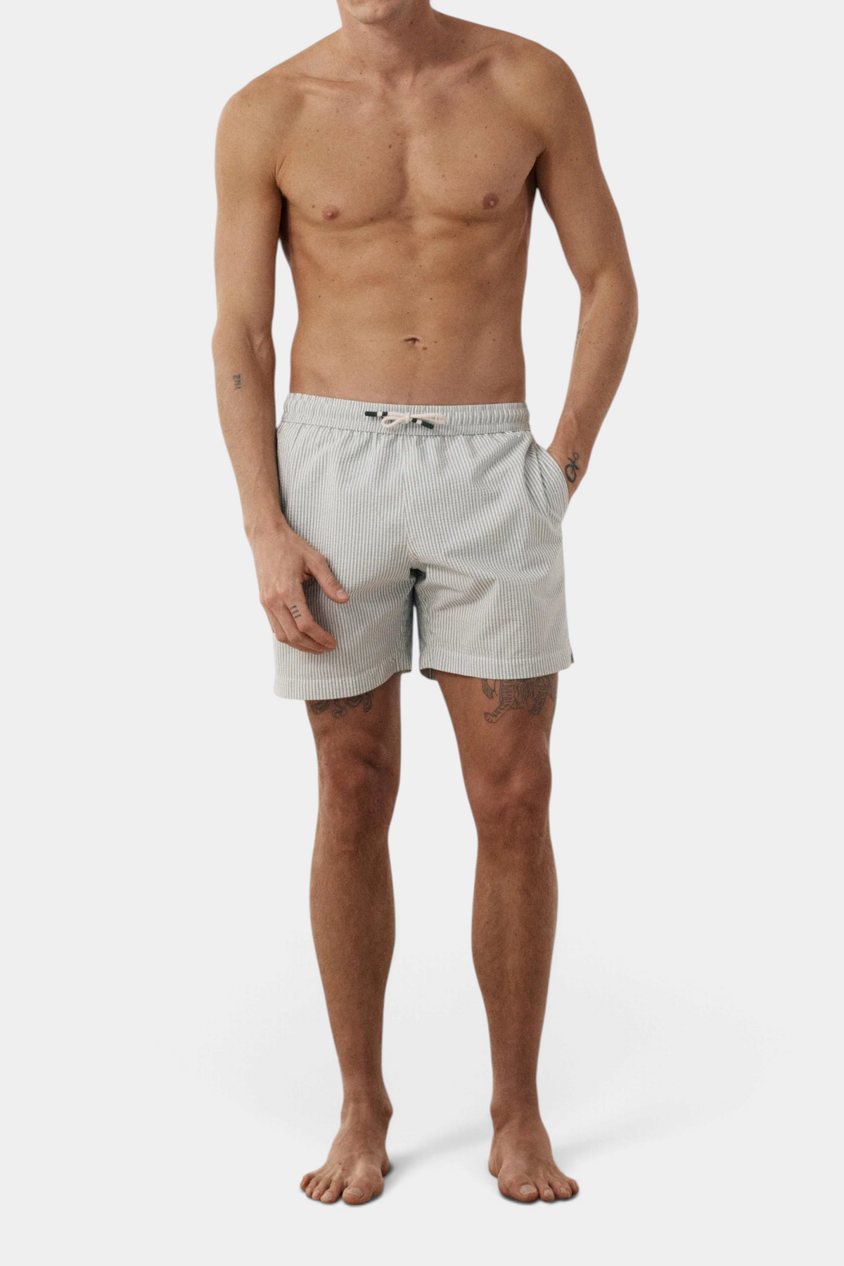 The Copper Shed men's green and white striped seersucker swim trunks with a textured finish worn by a model
