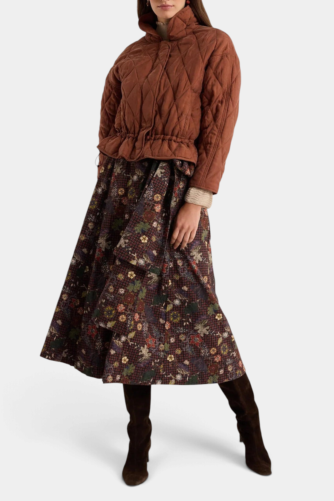 The Copper Shed Haisley quilted funnel neck jacket in tortoise brown with a drawstring waist worn over a floral skirt