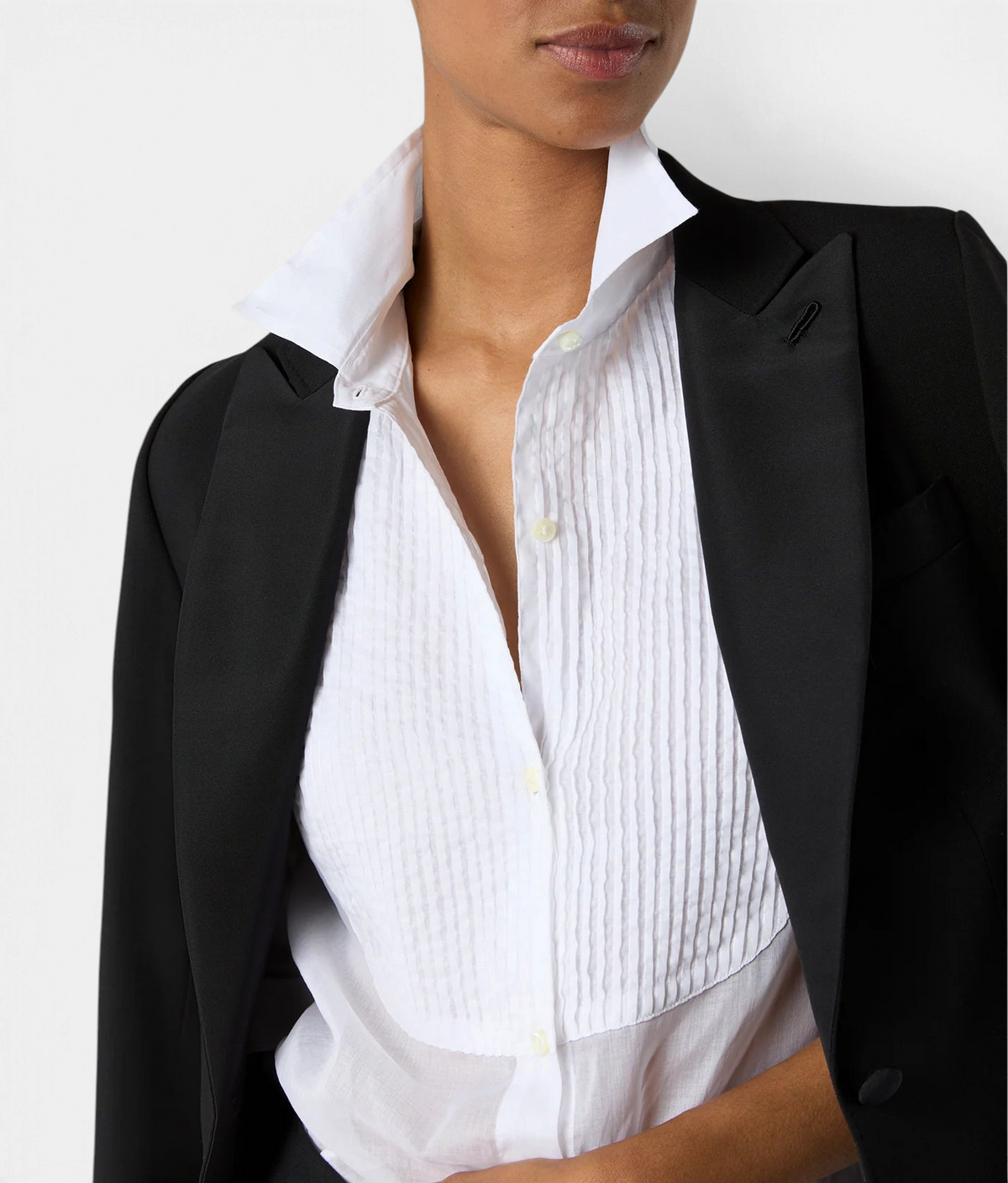 The Copper Shed Hattie shirt in white cotton organdy with a pleated bib front, worn under a black blazer.