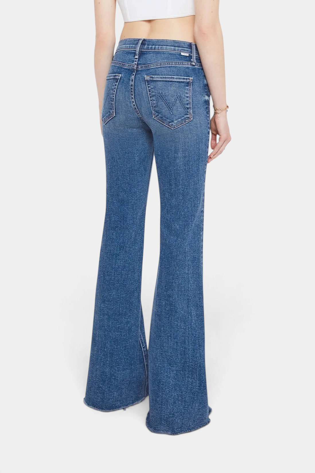The Copper Shed high-rise flare jeans in mid-blue stretch denim with a frayed hem, back view on a model