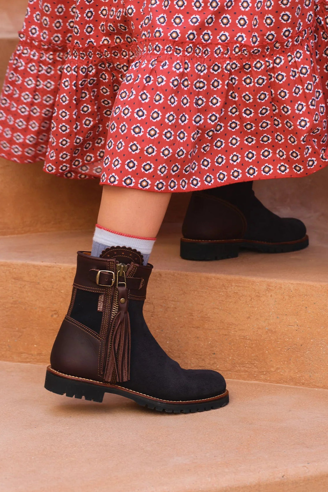 The Copper Shed Inclement cropped waterproof suede boots in dark brown with tassel detail worn with a patterned skirt