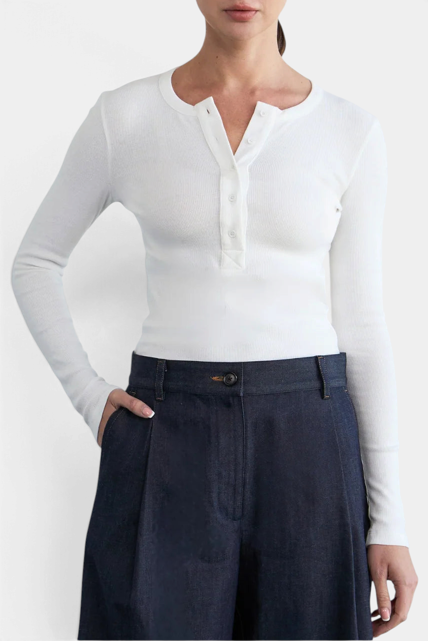 The Copper Shed Kaia long sleeve white ribbed cotton henley tee with a five-button placket worn with dark denim pants