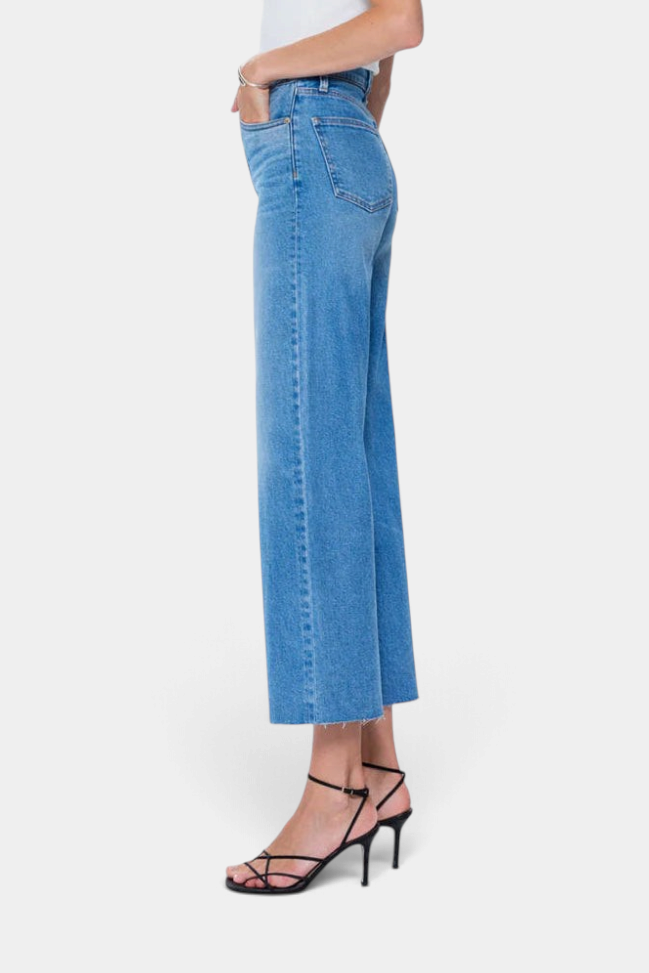 The Copper Shed Lana high rise cropped wide leg jeans in a lived-in blue wash with a raw hem, side profile view.