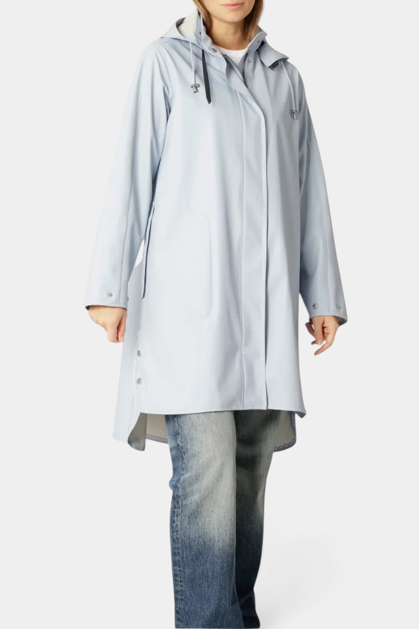 The Copper Shed light blue rubberized raincoat with a hood, welded seams, and a straight-fit design on a model.