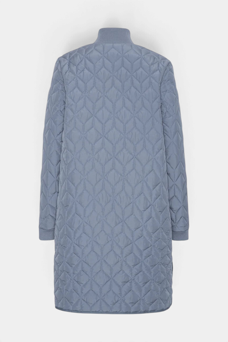 The Copper Shed long blue padded quilt jacket with a high ribbed neckline and geometric stitching, back view.