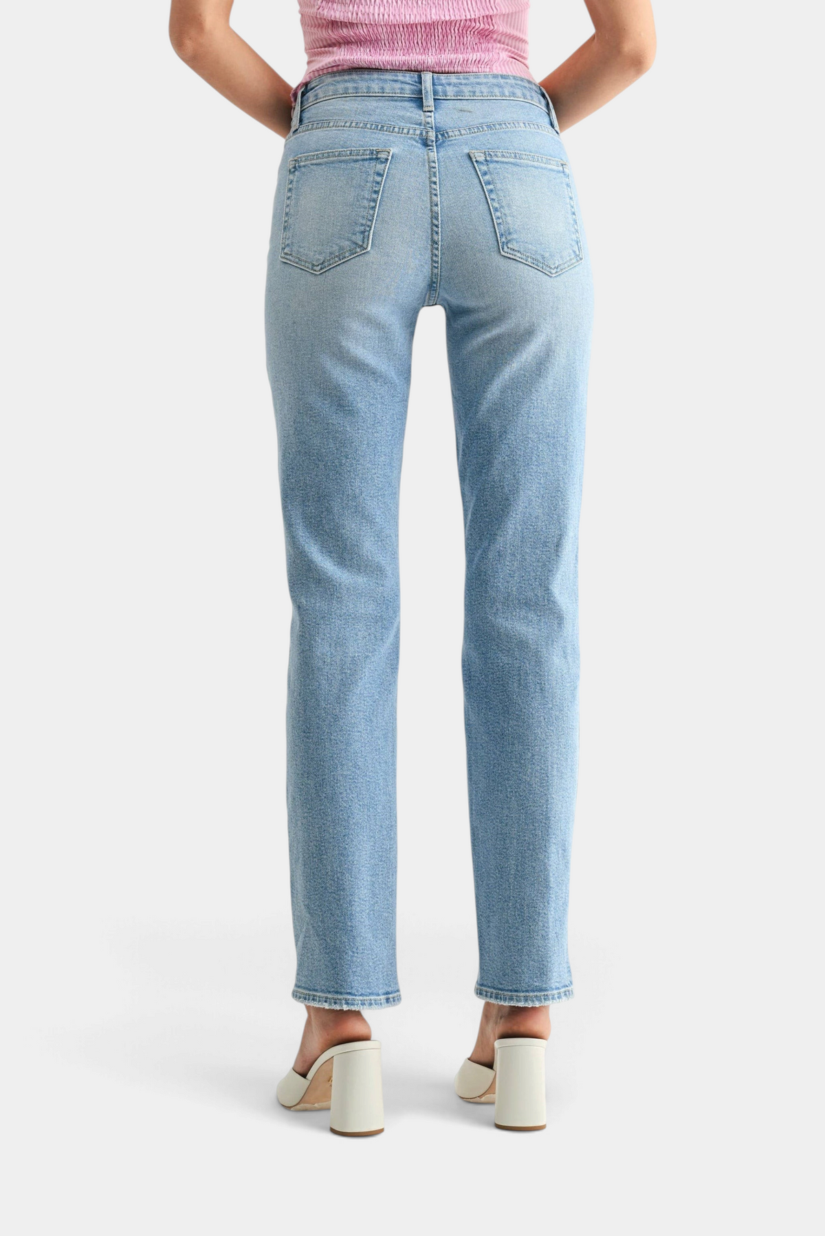 The Copper Shed mid-rise stovepipe straight leg jeans in light wash denim, back view on a model wearing white heels.