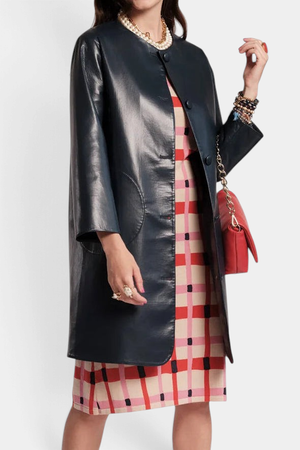 The Copper Shed Mod Jacket in black faux leather with a round collar and circular pockets worn over a patterned dress.