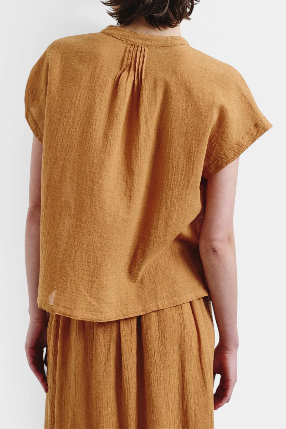 The Copper Shed organic cotton crepe gauze top in mustard yellow with short sleeves and pleated back detail.