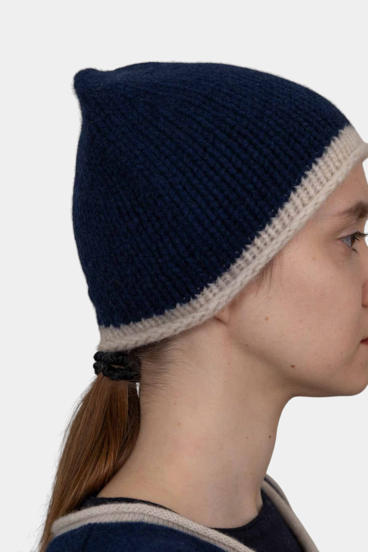 The Copper Shed navy blue hand-knitted organic cashmere beanie with a contrasting cream rolled edge on a model