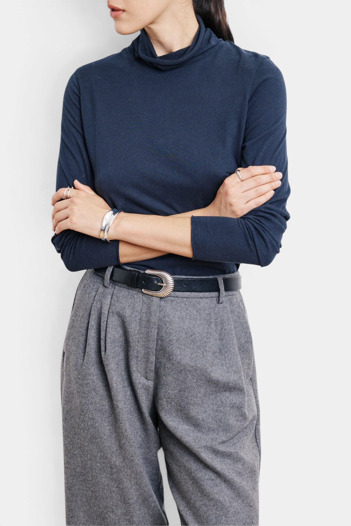 The Copper Shed navy long-sleeve knit T-shirt with a stand-up collar worn with grey trousers and silver accessories.