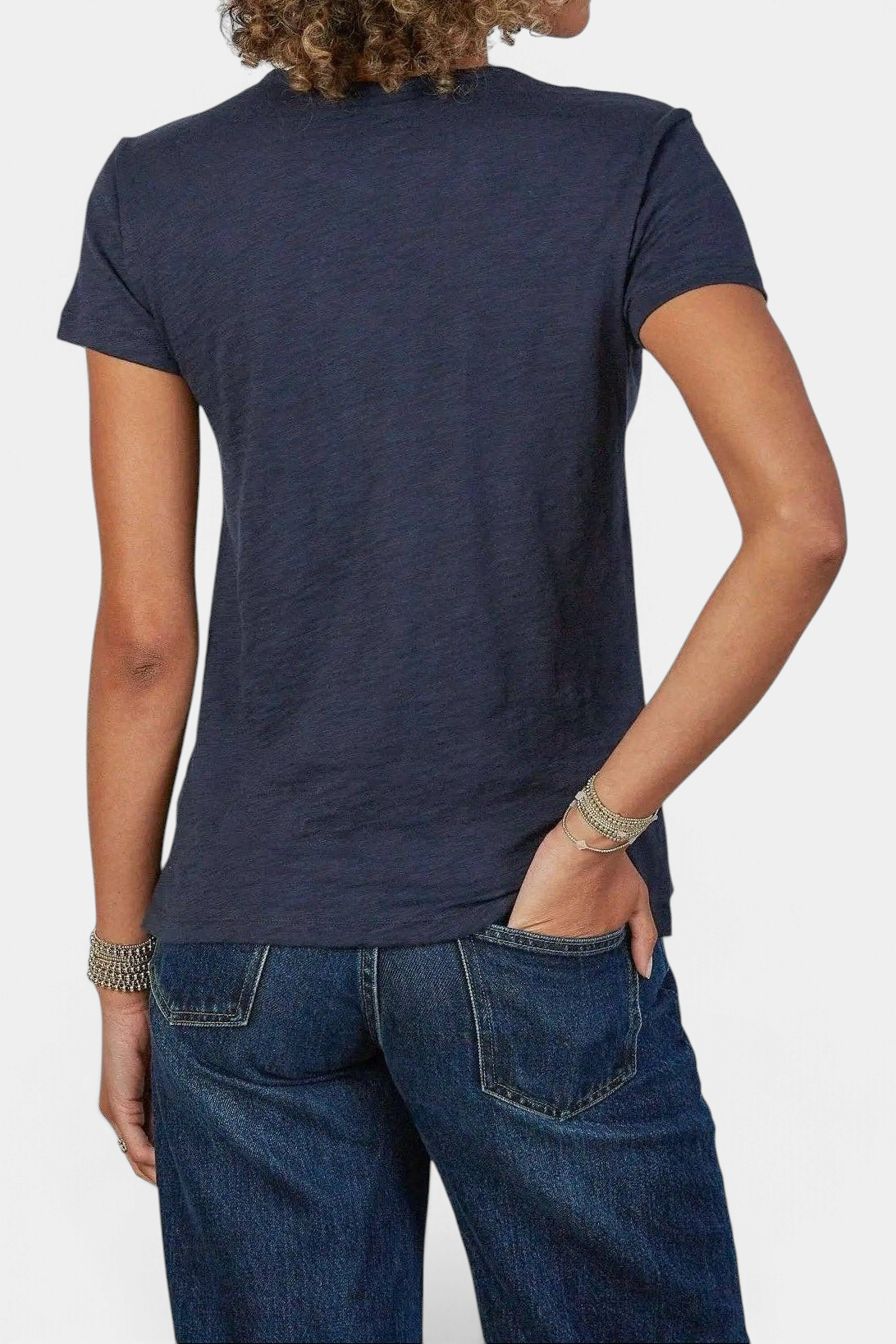 The Copper Shed navy pima cotton slub crew neck t-shirt worn by a woman with curly hair, back view.