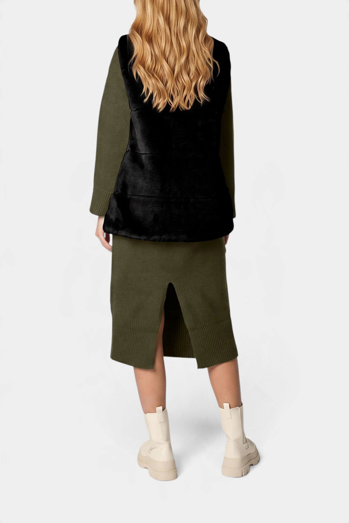 The Copper Shed Nives reversible faux fur vest in black worn over an olive green knit dress with cream boots