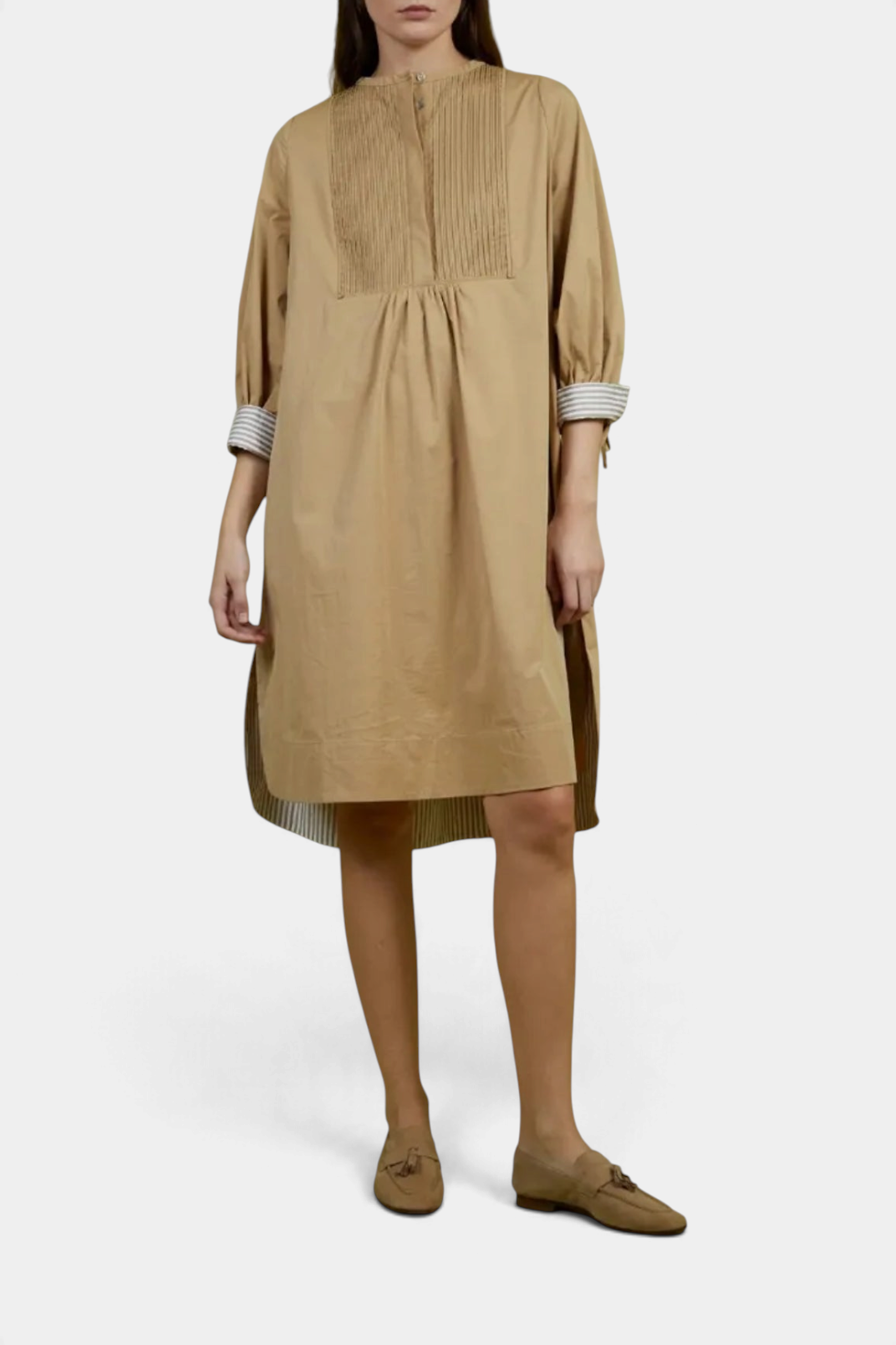 The Copper Shed Noemi shift dress in tan cotton with a gathered neckline, pintuck detail, and striped sleeve cuffs.