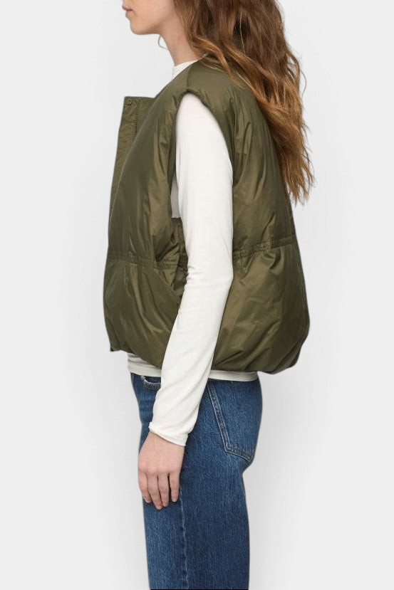 The Copper Shed Catarina olive green quilted nylon puffer vest worn by a model in a side profile view.