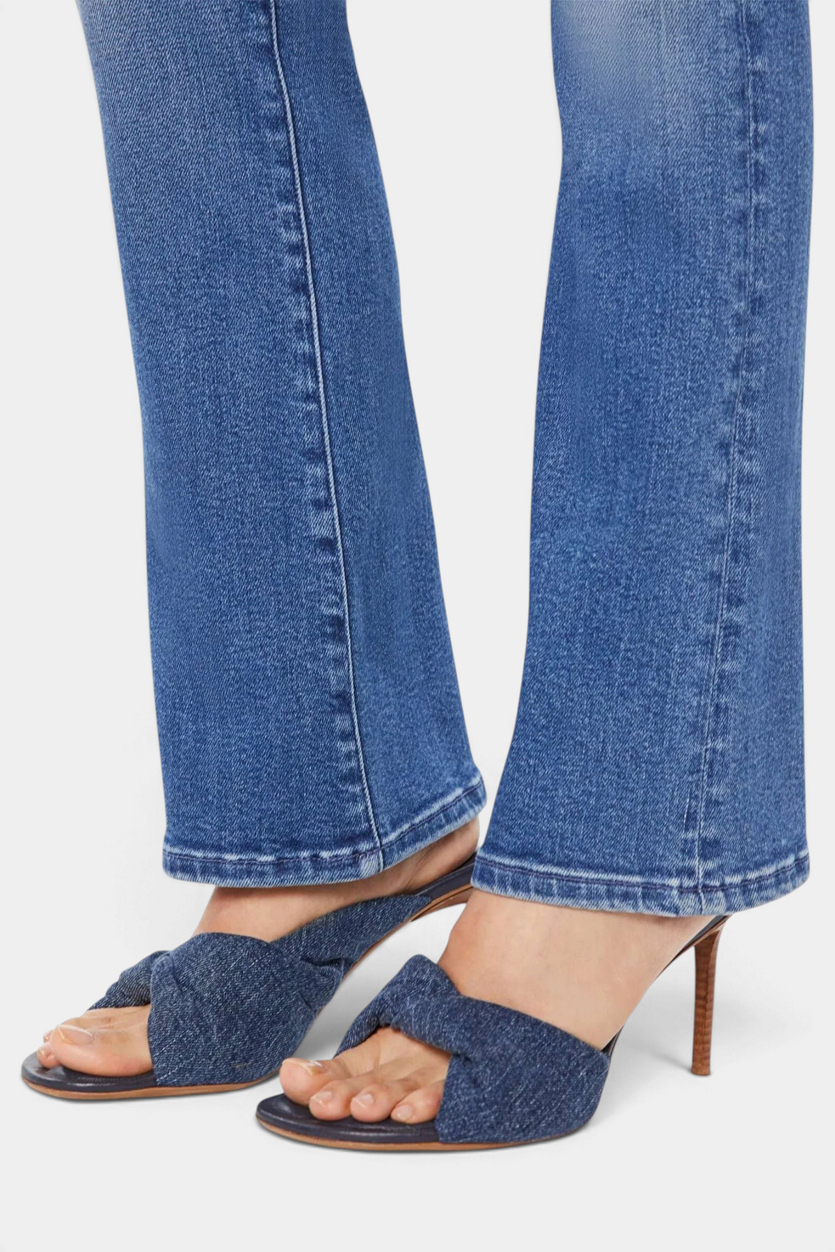 The Copper Shed mid-blue stretch denim flare jeans with a clean hem worn with knotted denim heeled sandals