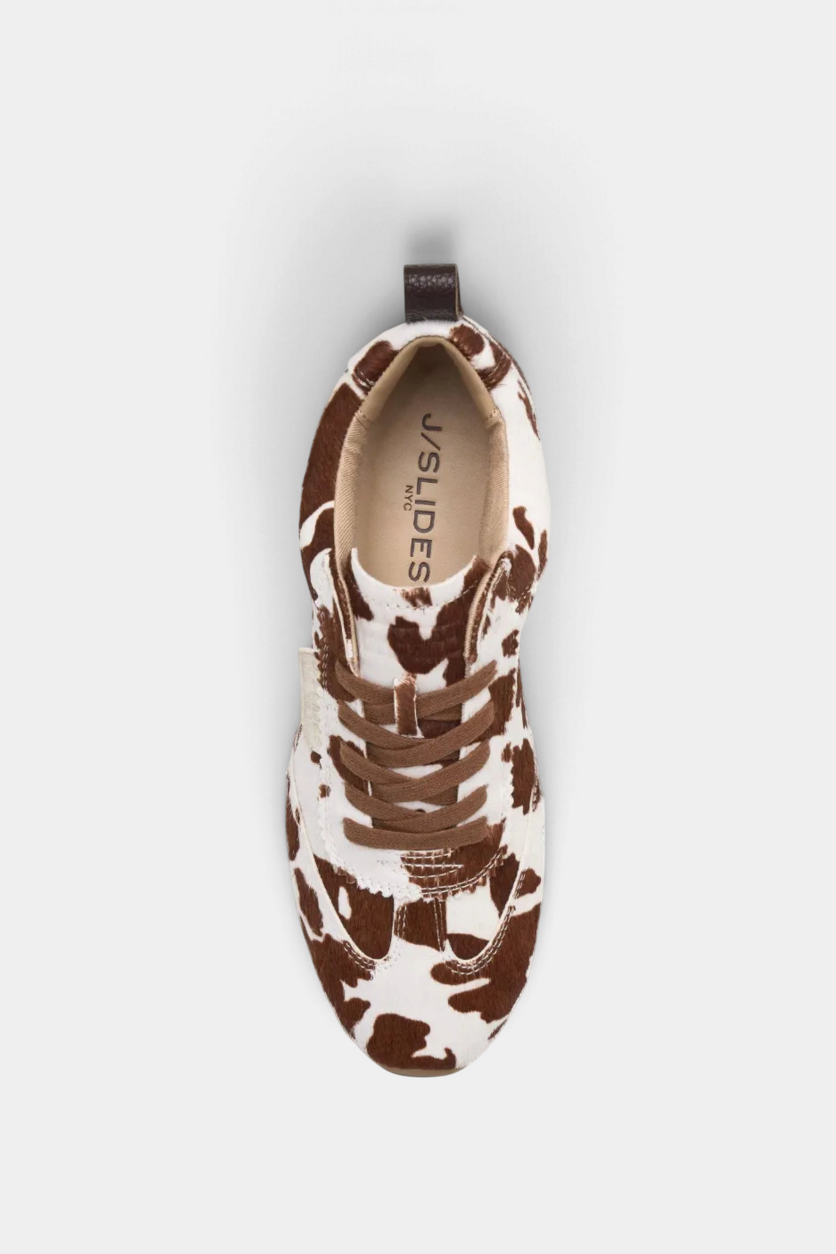 The Copper Shed Paige leather sneaker in a brown and white cow print pattern with a lace-up design