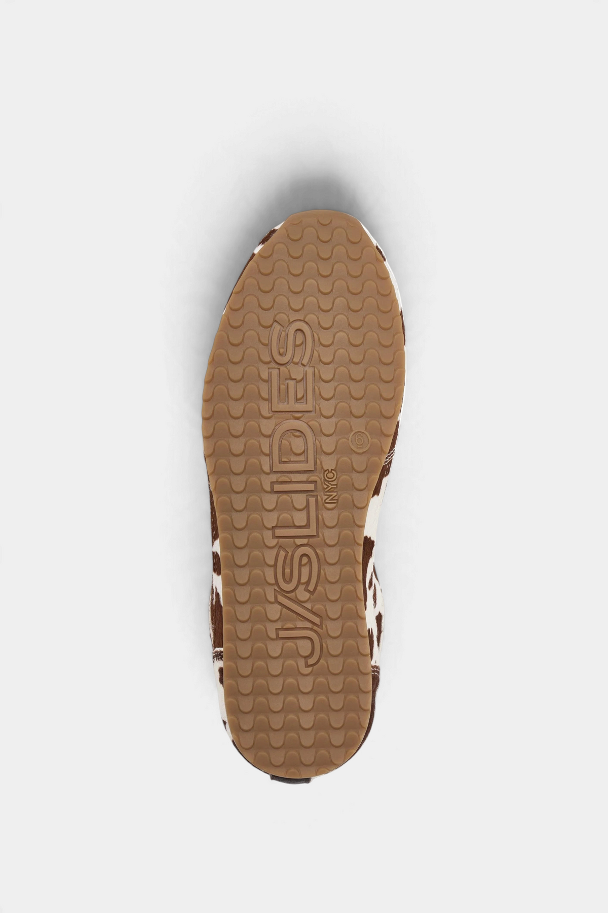 The Copper Shed Paige leather sneaker featuring a brown and white cow print pattern and a textured rubber sole.