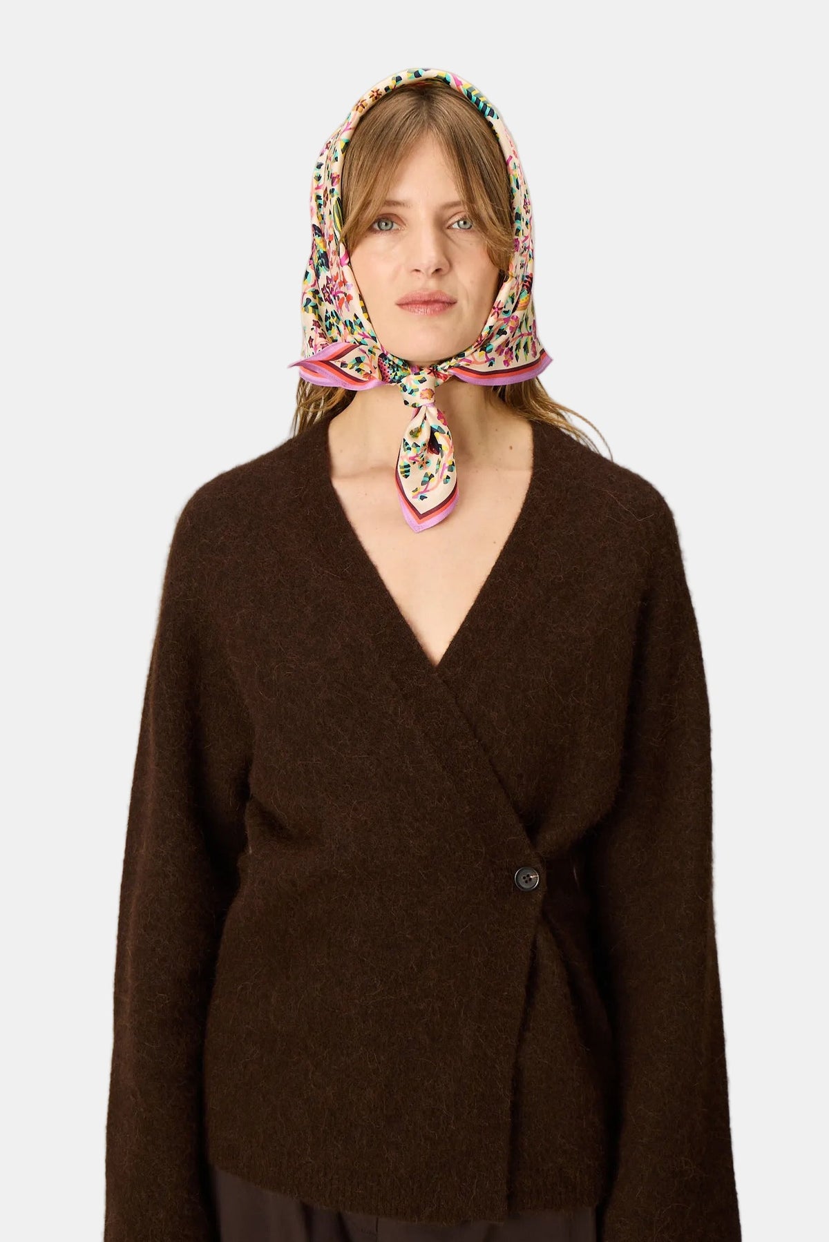 The Copper Shed Perrot white silk square scarf with colourful floral print worn as a headscarf by a woman