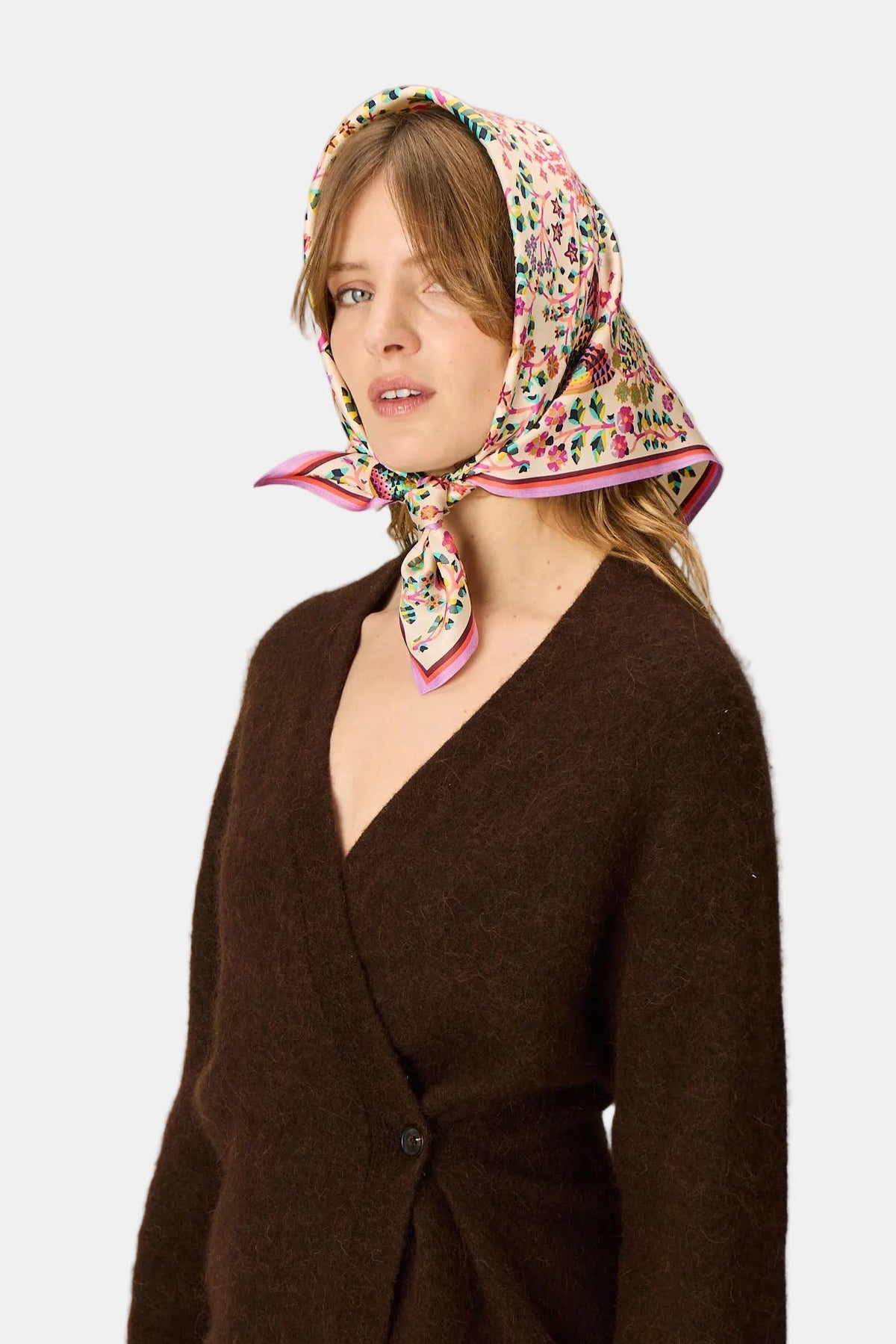 The Copper Shed Perrot square silk scarf in white with a colourful floral print tied around a woman's head