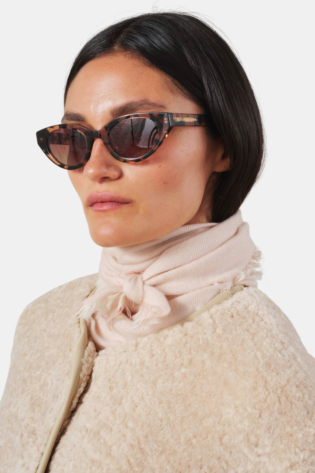 The Copper Shed light pink cashmere scarf with herringbone pattern and frayed edges worn knotted around the neck.