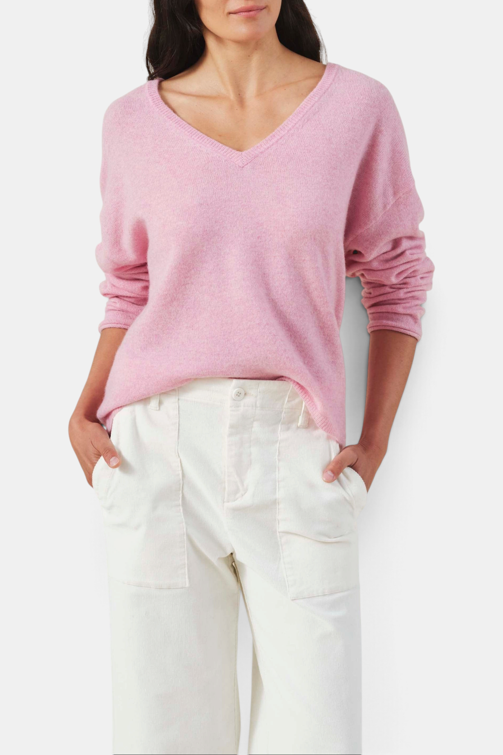 The Copper Shed pink cashmere sweater with a deep V-neckline, dropped shoulders, and ribbed trim on a model.