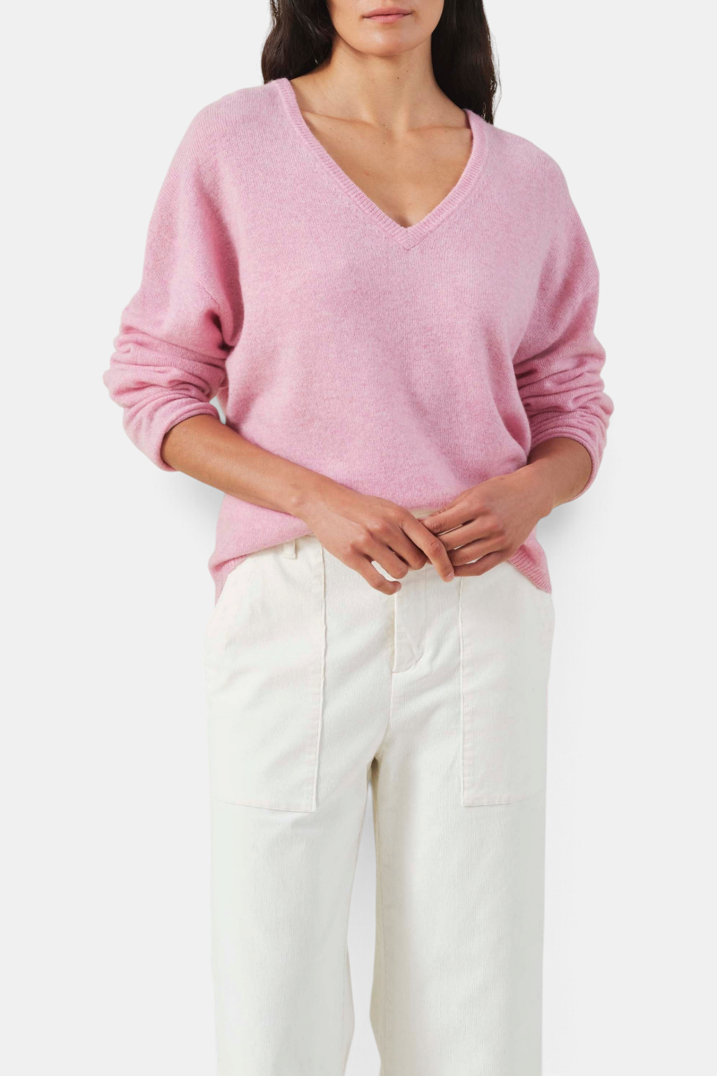 The Copper Shed pink cashmere sweater with a deep V-neck and dropped shoulders worn by a model.