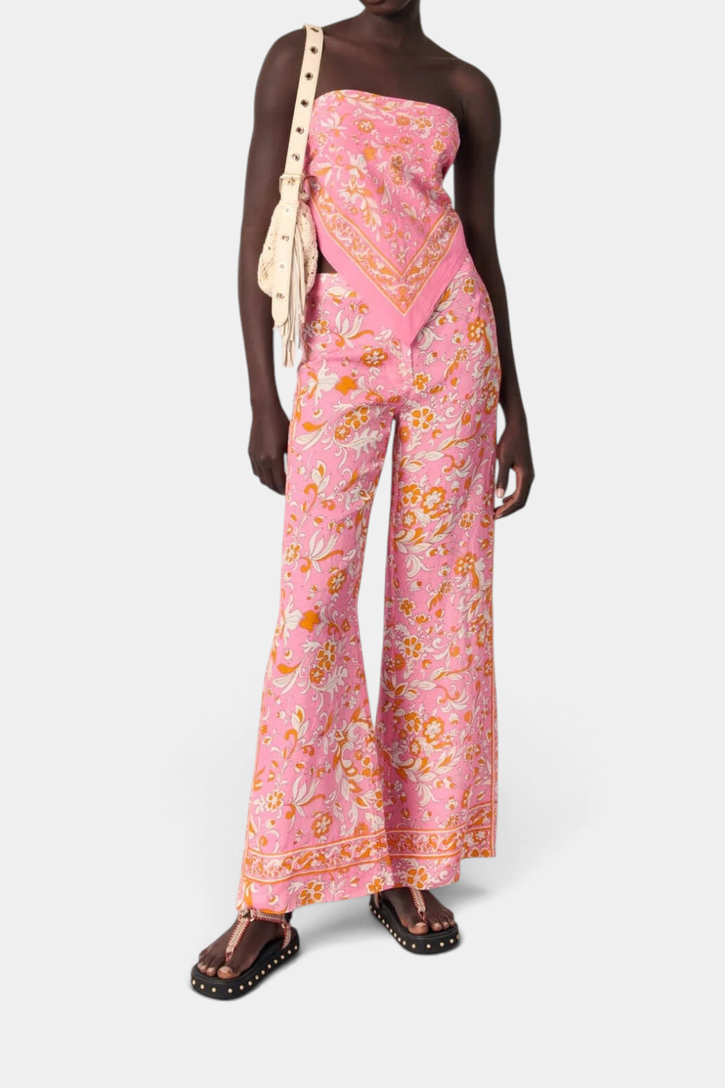 Model wearing The Copper Shed pink floral wide-leg linen trousers with a matching strapless top and studded sandals.