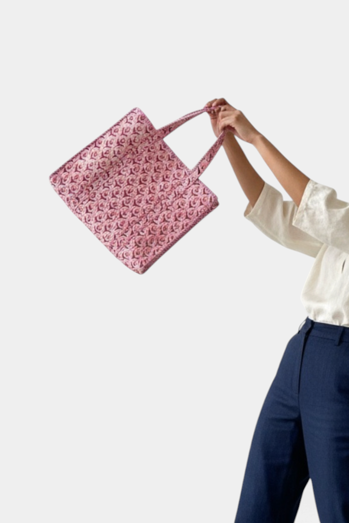 The Copper Shed pink quilted cotton tote bag with floral block print held by a person in a white shirt and blue pants