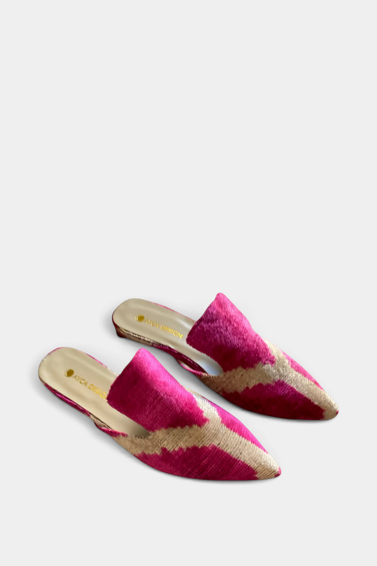 The Copper Shed silk velvet ikat pointed-toe slides in vibrant pink and gold with an open-back design.