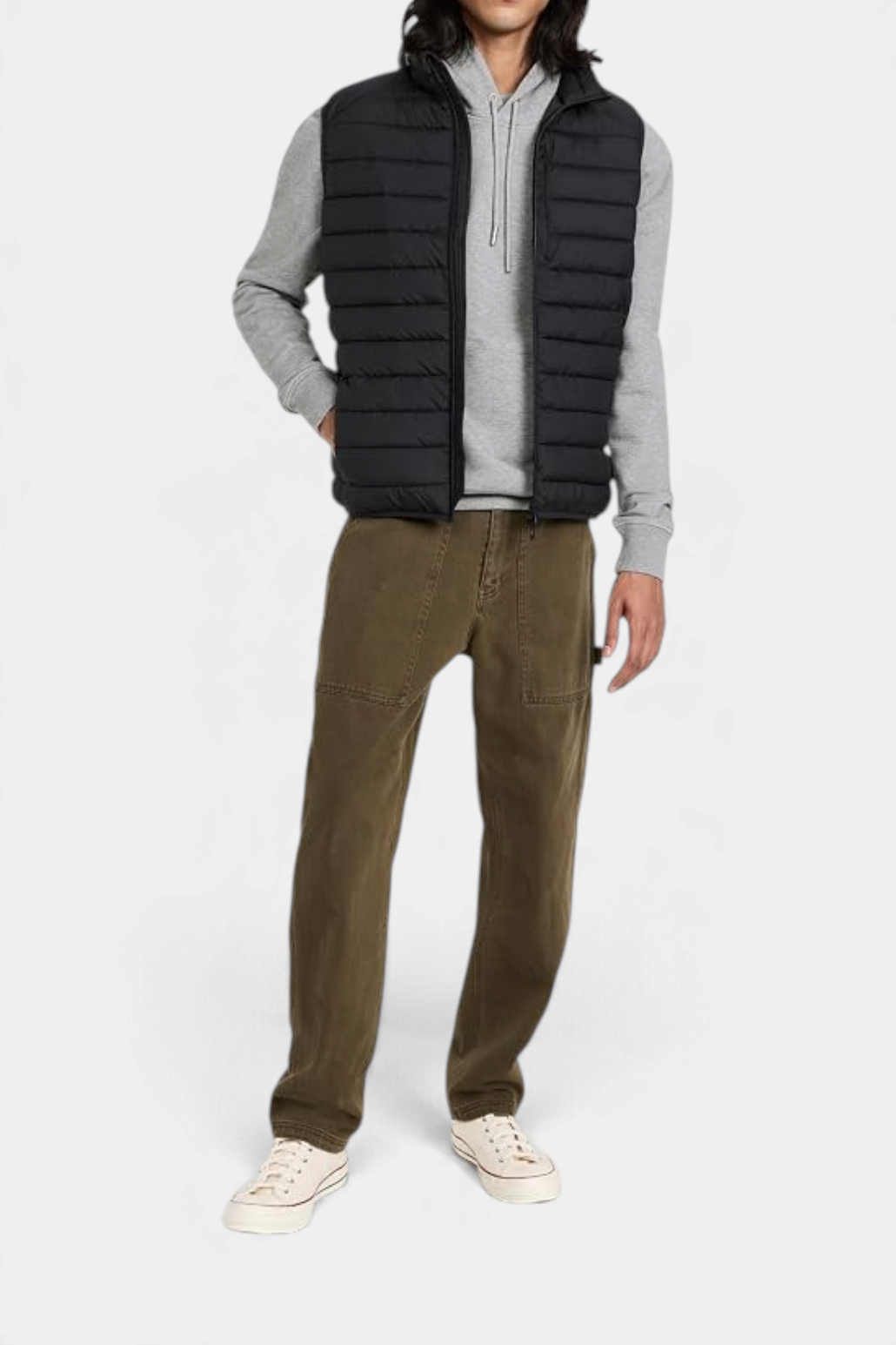 The Copper Shed Rhus men's black quilted puffer vest with stand-up collar, worn over a grey hoodie and olive trousers.