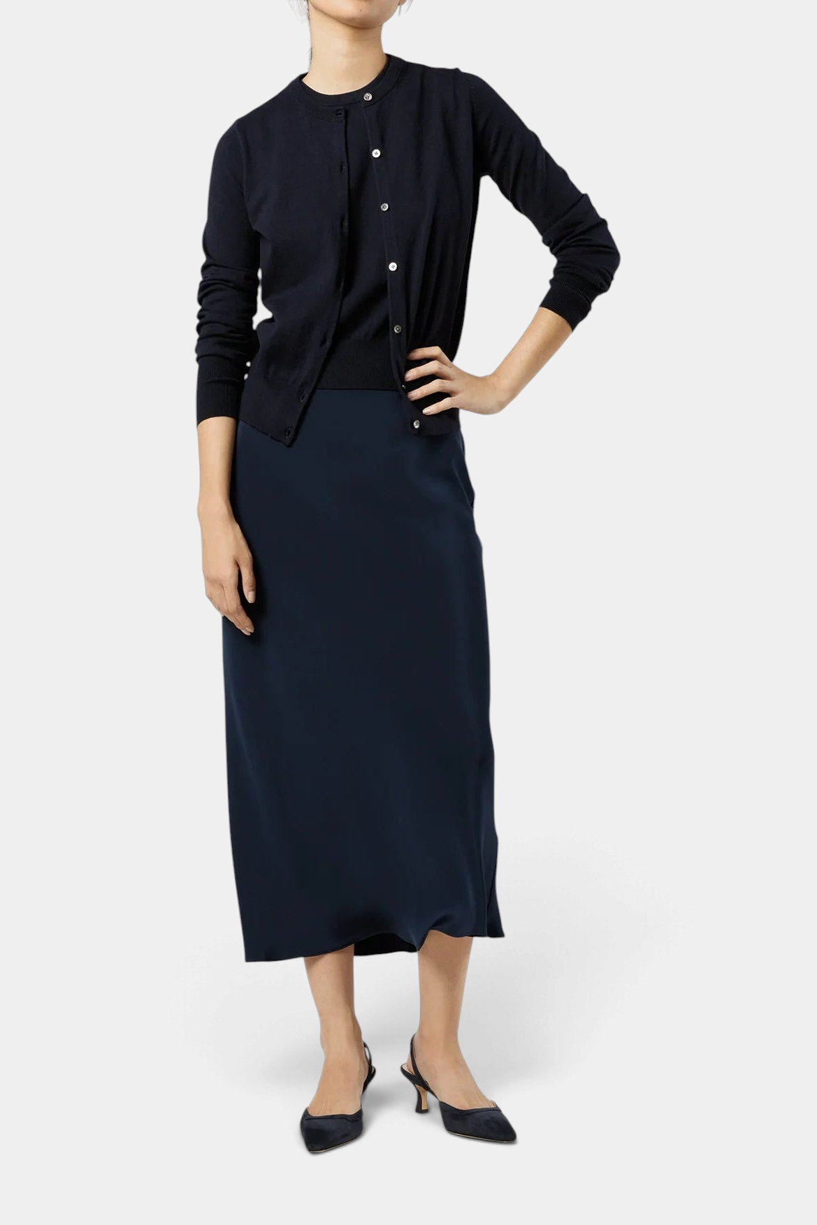 The Copper Shed Rosie cardigan in navy cotton-silk knit with mother-of-pearl buttons, worn as a top with a midi skirt.