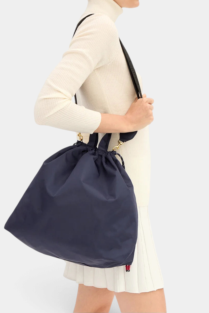 The Copper Shed Sac Tout navy recycled polyester drawstring bag worn as a crossbody with short handles.