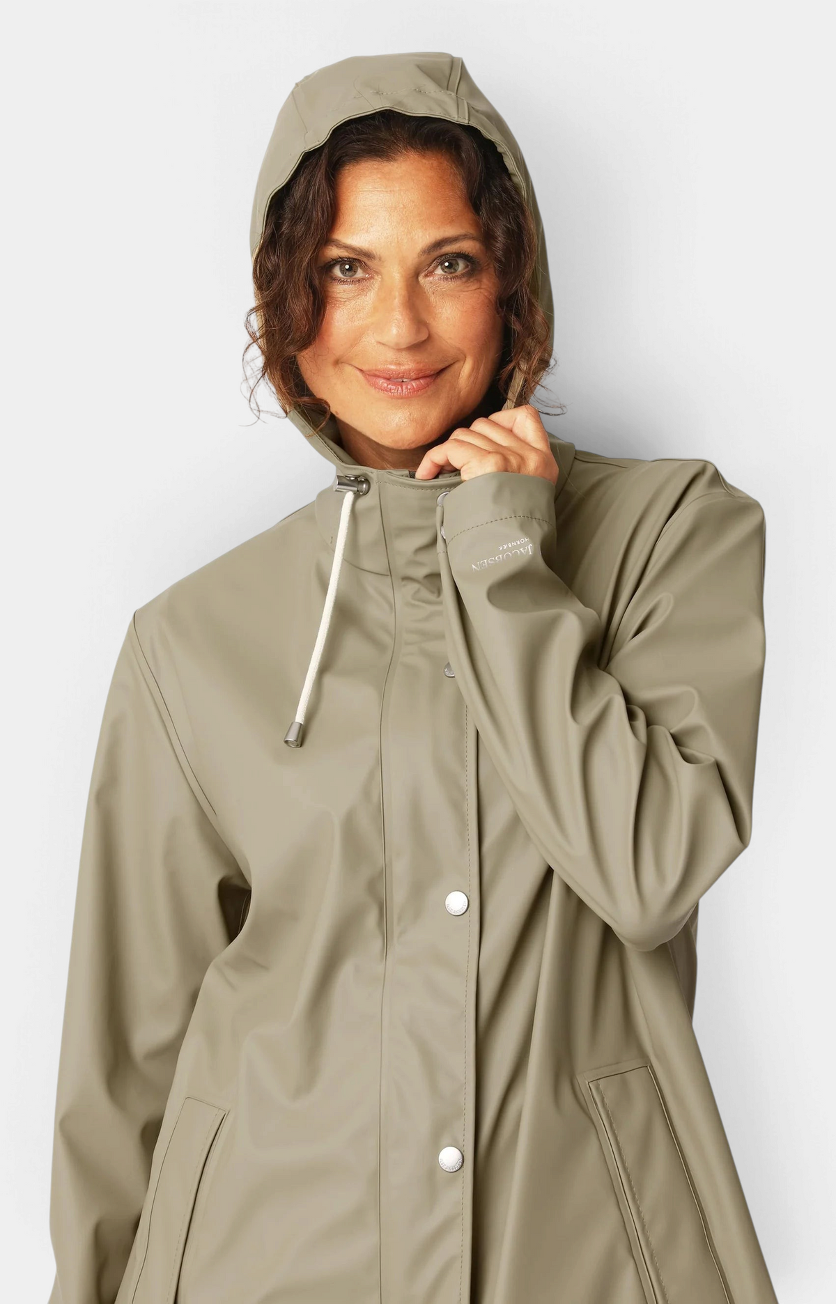 Woman wearing The Copper Shed olive green rubberized PU raincoat with a hood and white drawstring