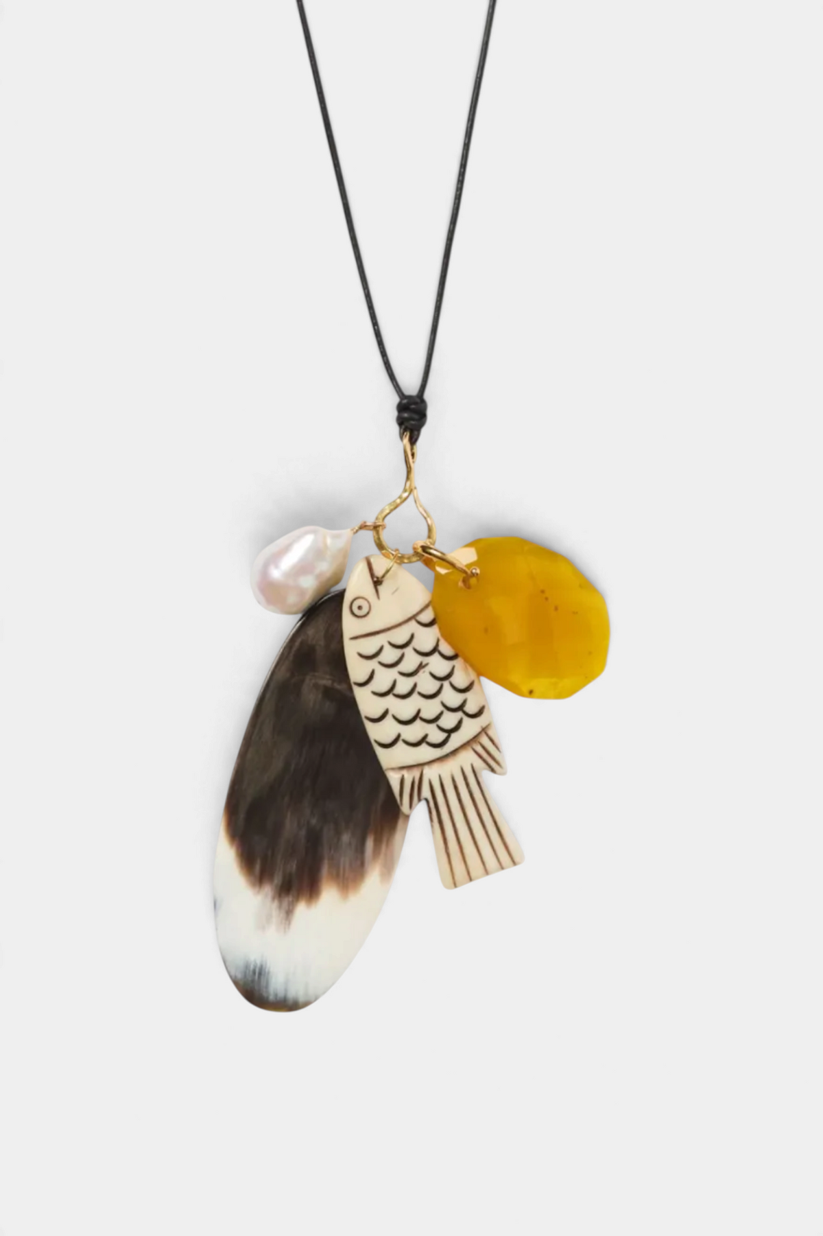 The Copper Shed Shoal Charm Necklace featuring a carved bone fish, yellow resin, and baroque pearl on a black cord.