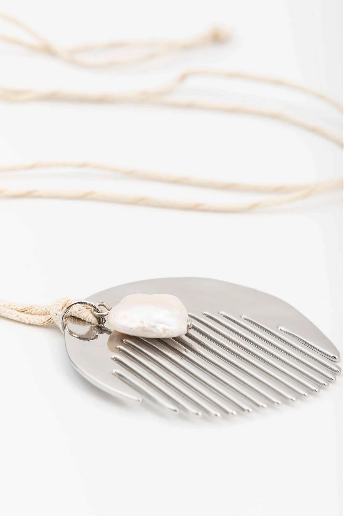 The Copper Shed long necklace featuring a silver-plated zamak comb pendant adorned with a natural pearl on silk cord