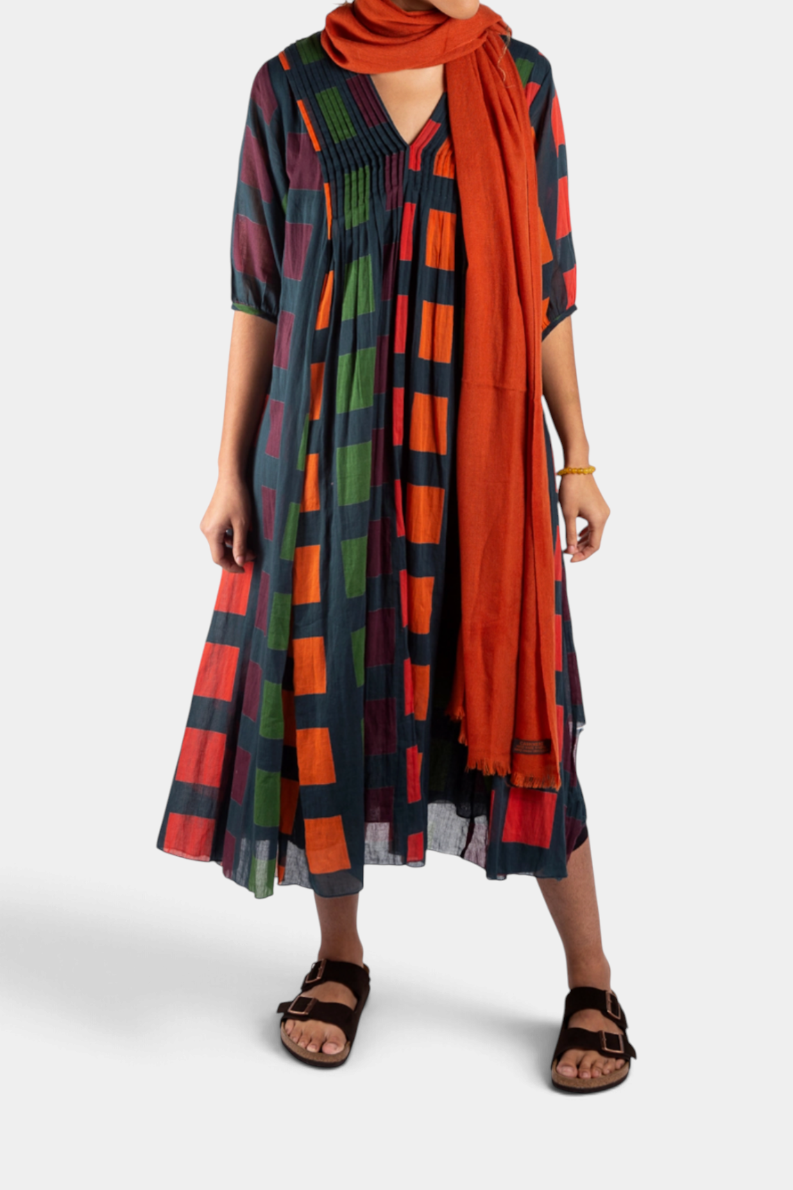 The Copper Shed Skye midi dress in petrol with a multi-colored block print, 3/4 sleeves, and front pleat detail.