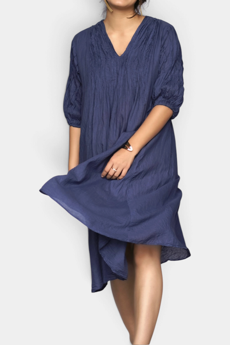 The Copper Shed Skye Dress in petrol blue cotton with 3/4 sleeves, delicate front pleating, and a midi-length hem.