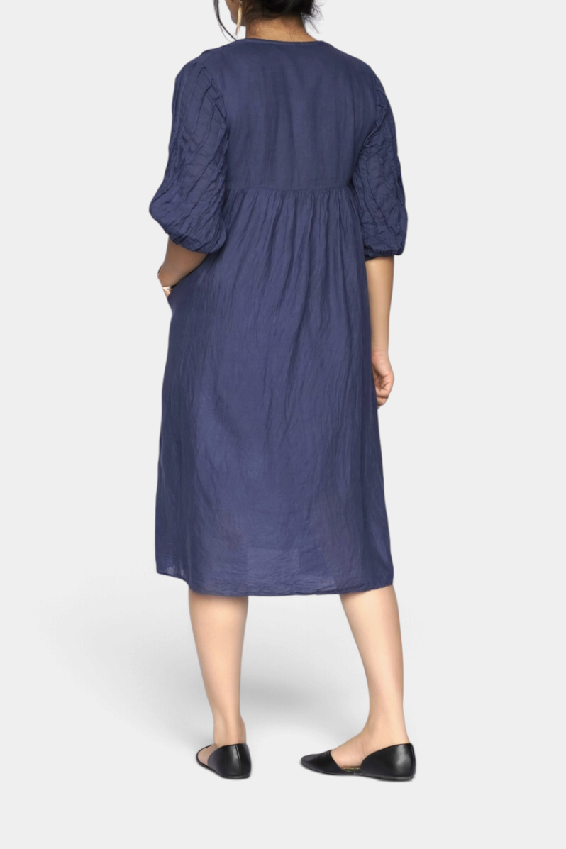 The Copper Shed Skye midi dress in petrol blue cotton with 3/4 sleeves and pleated texture, back view.