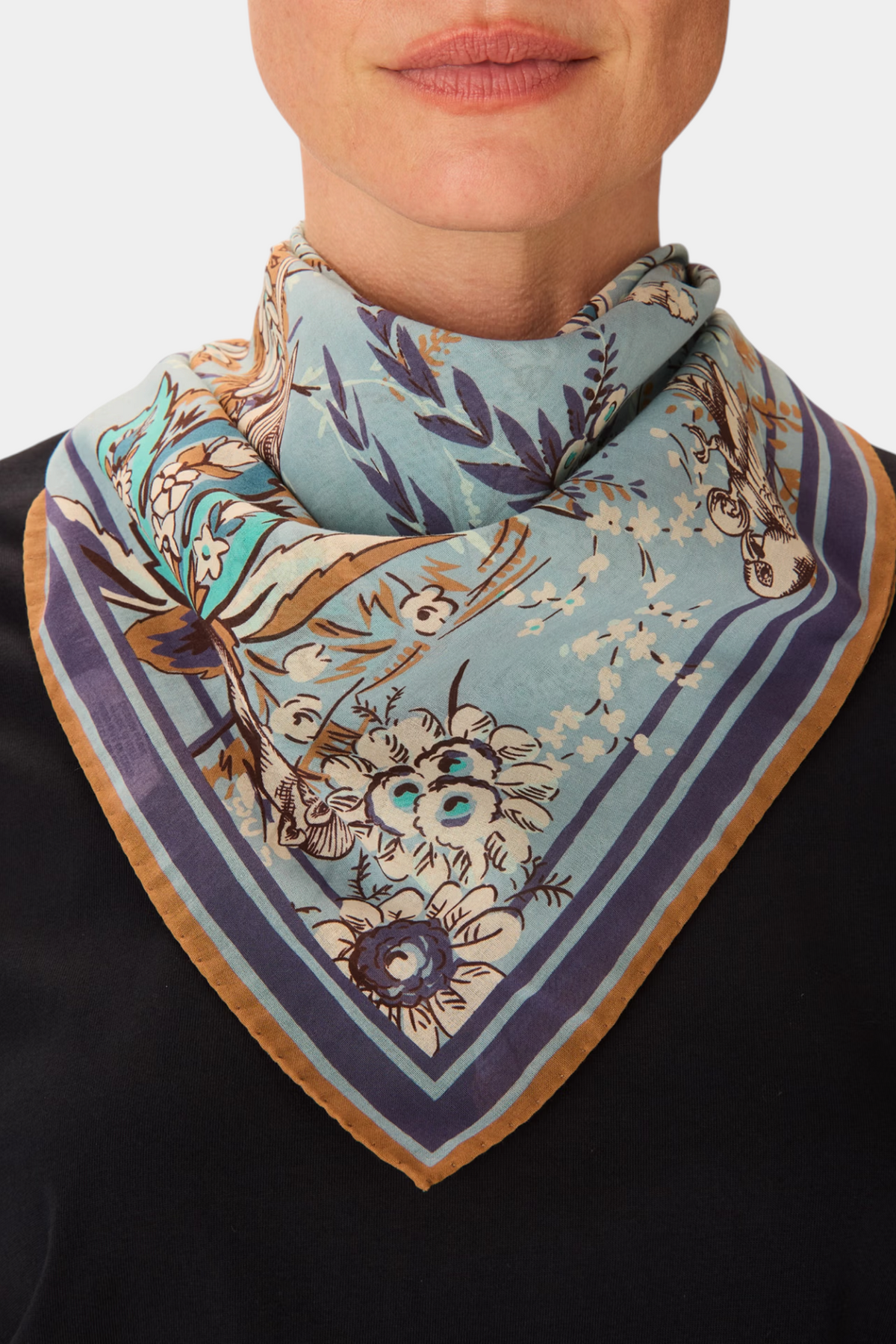The Copper Shed Square 70 Pagode scarf in blue cotton with floral patterns worn around the neck.