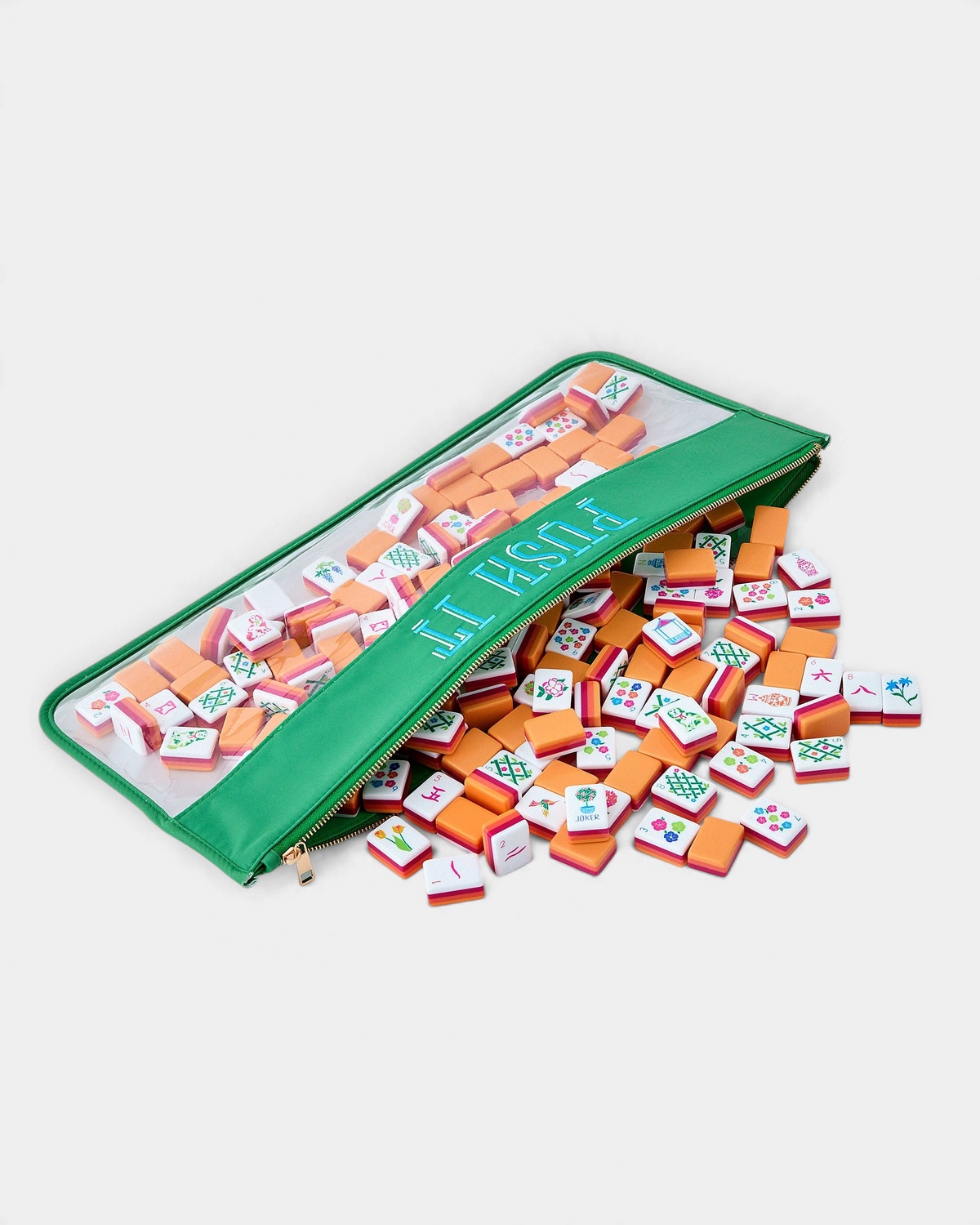 The Copper Shed Sunset Tiles set featuring vibrant coral, orange, and neon pink acrylic mahjong tiles in a green case.