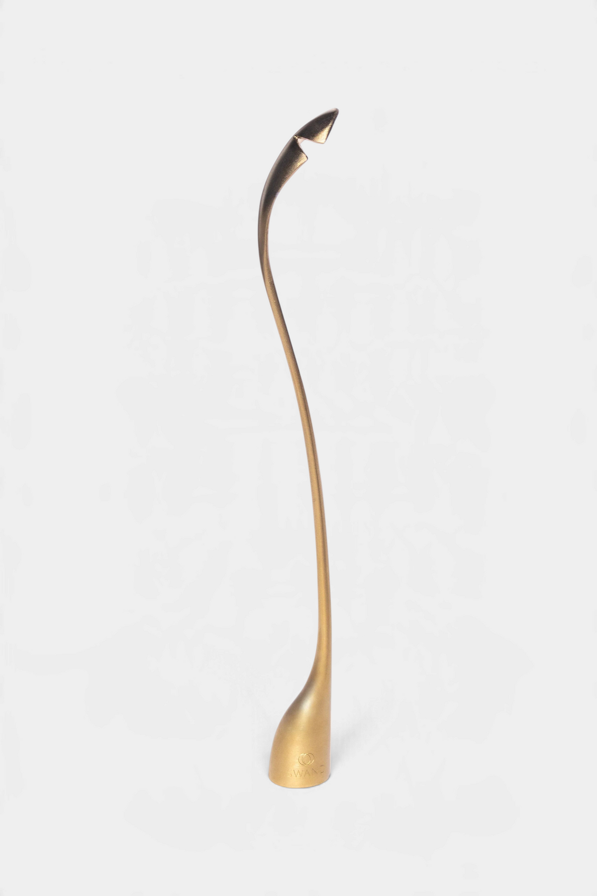 The Copper Shed SWAND 4-in-1 gold candle care tool featuring a sleek, curved design for wick maintenance.