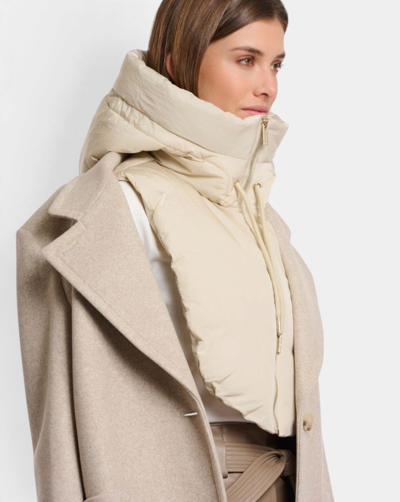 The Copper Shed Rino & Pelle Tabita padded bib in peated beige worn over a coat for extra warmth and style.