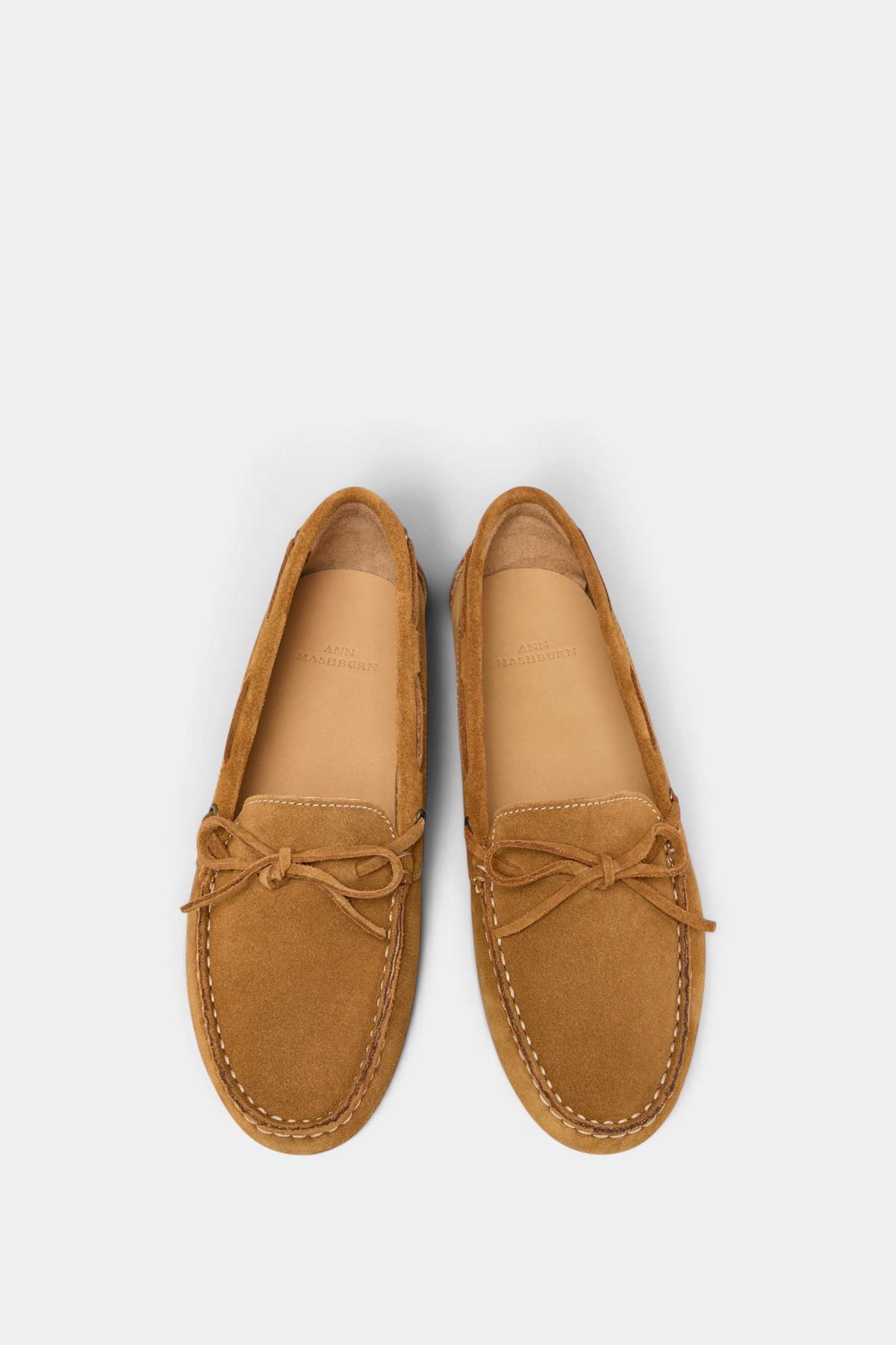 The Copper Shed tan suede driving moccasins with a slip-on profile, bow detail, and comfortable padded insole.