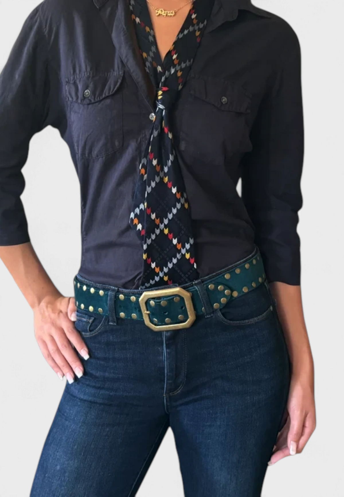 The Copper Shed teal suede belt with a rectangular squared-off buckle and metal studs worn with dark denim jeans.