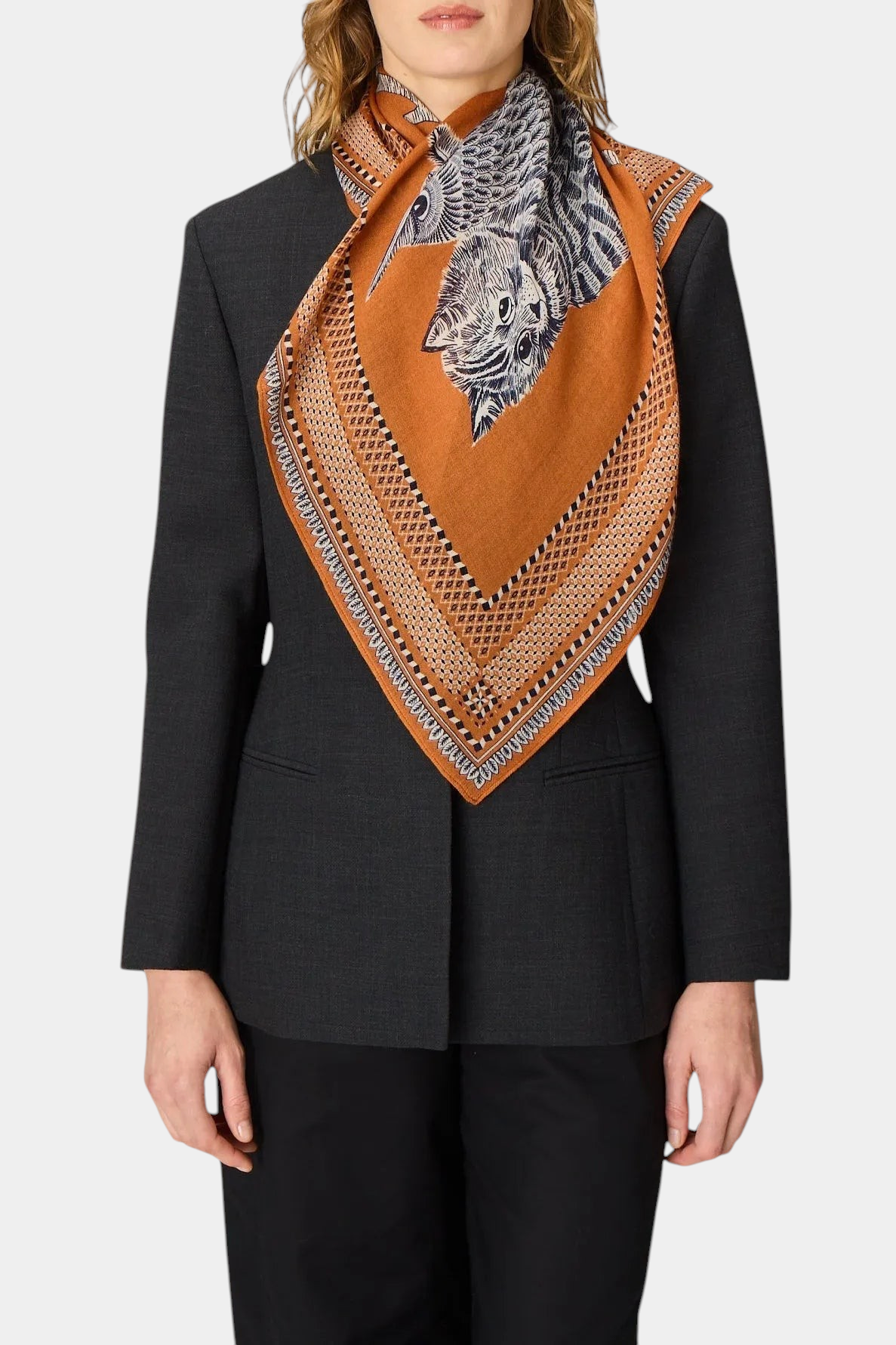 The Copper Shed Square 70 Chouette scarf in terracotta wool with an owl print, worn draped over a dark blazer.