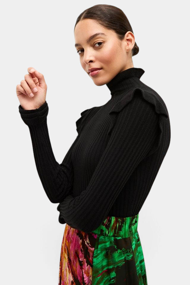 The Copper Shed Tinley black ribbed turtleneck sweater featuring ruffle trim on the collar and cuffs on a model